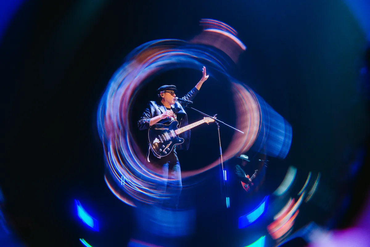 Long-exposure concert photo with swirling light trails framing guitarist